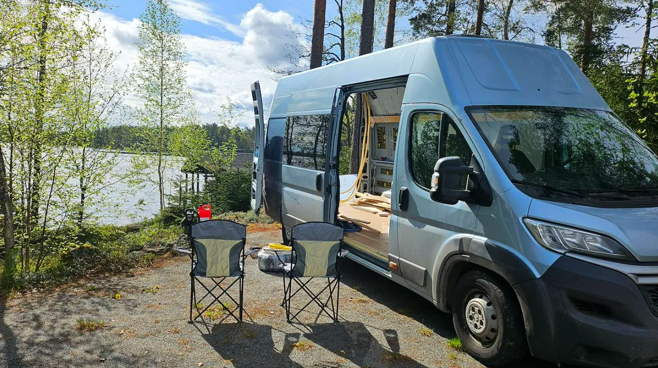 INN-300 järven rannalla, sivuovi auki ja rakennustarvikkeet sisällä